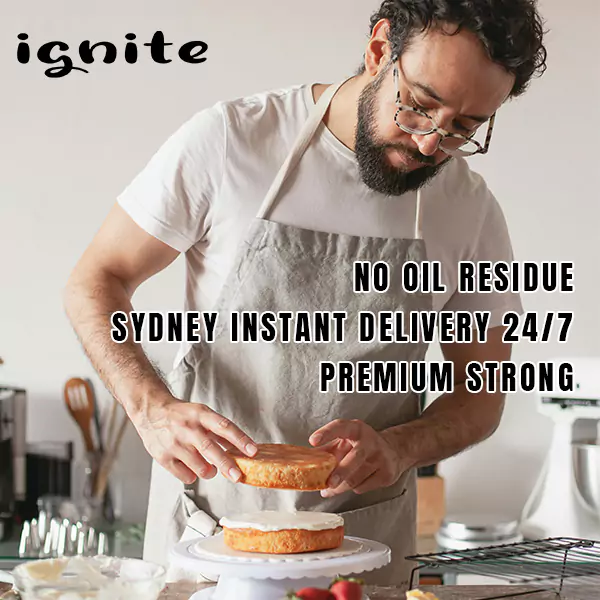 The image features a person wearing glasses and an apron, focused on carefully placing a cake layer onto another on a cake stand. The kitchen environment appears well-equipped for baking, with a whisk and other kitchen tools in the background. Overlaying the image are phrases promoting service attributes such as "no oil residue," "Sydney instant delivery 24/7," and "premium strong." This text suggests the image is part of an advertisement for a baking-related product or service, emphasizing efficiency, cleanliness, and strength, with a particular focus on Sydney as the service area.
