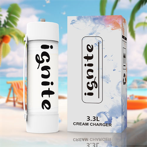In this image, we see an oversized cream charger canister standing upright on a sandy beach. The canister is white with "ignite" written in a large, bold, black font along its side. The setting is a sunny beach scene with a vibrant blue sky, fluffy white clouds, calm blue waters, and various beach items such as a beach chair, a hat, a beach ball, and an inflatable orange ring. Palm trees are also visible, adding to the tropical vibe. The scene is likely meant to be humorous or attention-grabbing, juxtaposing the ordinary kitchen item with an idyllic beach backdrop.