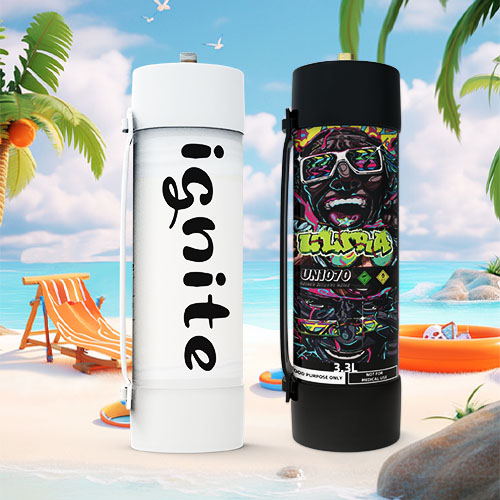 The image presents two oversized cream charger canisters side by side on a beach. The canister on the left is white with the word "ignite" written in a large, black, cursive font along its side. The canister on the right is black with a colorful, graffiti-style design and the word "UNIJOY" prominently displayed. It also has the net weight of "640g" indicated and is labeled for "food use only." Both are set against a beach scene that includes a lounge chair, a beach ball, a sun hat, and an orange inflatable ring, with palm trees, rocks, and the ocean under a blue sky. The contrasting designs of the canisters bring an urban, vibrant flair to the tranquil beach setting, merging culinary function with leisurely beach imagery.