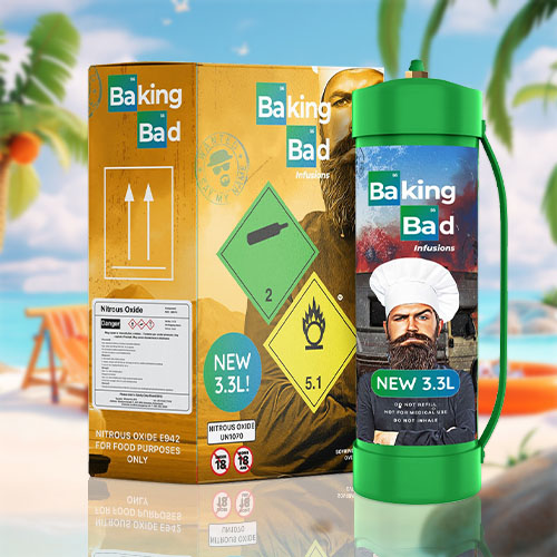 In the image, there's a product set for "Baking Bad Infusions" which includes a canister and a box. The canister, with a green label, features a graphic of a bearded man wearing a chef's hat and indicates "NEW 3.3L" as its size. The box echoes this branding and color scheme, with additional details such as "Nitrous Oxide E942 For Food Purposes Only," along with shipping and safety icons that include hazard symbols and a notice of flammability. Set on a beach with a tropical backdrop that includes palm trees, a sandy shore, and an inflatable ring floating in the ocean, the product contrasts with the leisurely beach setting, suggesting a theme of culinary adventure or creativity.
