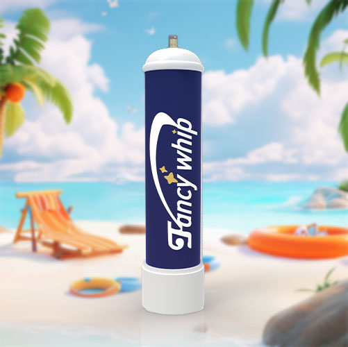 The image displays a large cream charger canister with a sleek design featuring the brand name "Fancywhip" in a curved banner over a stylized yellow star. The main body of the canister is a deep navy blue, contrasting with the white top and bottom caps. Positioned prominently on a sunny beach setting, the scene includes a deck chair, a colorful beach ball, a sun hat, and an inflatable orange ring floating near the shore. Palm trees line the background, with a serene blue ocean and a sky dotted with fluffy clouds, creating an overall impression of a perfect day at the beach. The clean and modern look of the canister stands out against the natural beach elements, suggesting a blend of culinary art with the relaxed vibes of a seaside escape.