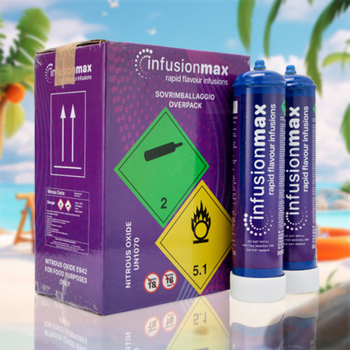 The image shows a set of "InfusionMax" cream chargers. On the left, there's a purple box with a vivid green label reading "NITROUS OXIDE FOR FOOD PURPOSES ONLY," along with hazard symbols and safety information, including warnings about flammability and age restrictions. On the right, two canisters are displayed; they have a matching deep blue and purple design that reads "InfusionMax rapid flavour infusions," suggesting their use for culinary purposes. The canisters and box are set against a sunny beach backdrop, featuring clear blue skies, palm trees, and typical beach leisure items, providing a sharp contrast to the culinary-focused products.
