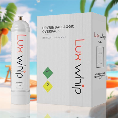 The image displays a large cream charger canister labeled "Luxwhip" in a tall, elegant font, positioned in the center of a sunny beach landscape. The canister is a minimalist white, with the brand name accented in a soft, contrasting color. The scene includes a reclining orange deck chair, a beach ball, a blue sun hat, and an orange inflatable ring on the sandy shore. Palm trees, rocks, and a serene ocean under a clear blue sky with light clouds complete the idyllic beach setting. Warnings on the canister include "Do not refill," "Food use only," and "Do not inhale," indicating its intended culinary use and safety precautions. The canister's sleek, luxurious design contrasts with the laid-back, cheerful beach environment.