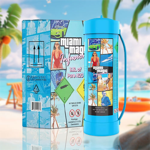 The image presents a cream charger canister with a "Miami Magic" theme, featuring images that evoke the lively atmosphere of Miami, including palm trees, sun, and stylish people. The canister is turquoise, complementing the beach setting in which it is placed. The canister has a handle, indicating its large size and perhaps enhanced functionality. The beach scene is complete with a sun chair, a beach ball, a sun hat, and an orange life ring, set against a backdrop of a sandy shore, palm trees, and a clear blue sky with a calm sea. The design of the canister, coupled with the idyllic beach setting, suggests a blend of festive culinary experiences with the laid-back, sunny vibes of Miami life.