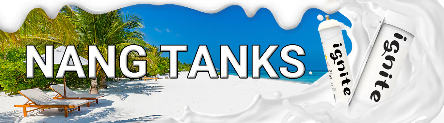 The image is a promotional banner with the words "NANG TANKS" prominently displayed in the center. The background features a beautiful tropical beach scene with white sand, palm trees, and sun loungers under a clear blue sky. On the right side, there is a creative representation of whipped cream that morphs into cream charger canisters with the label "ignite," reinforcing the theme of the product. The banner likely advertises cream chargers, colloquially known as "nangs," and is designed to capture the attention of potential customers with its bright, summery imagery and connection to leisure and enjoyment.